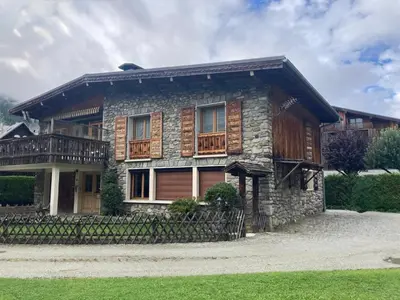 a stone house with a wooden balcony on it at Chalet d'Honneur in Chamonix-Mont-Blanc