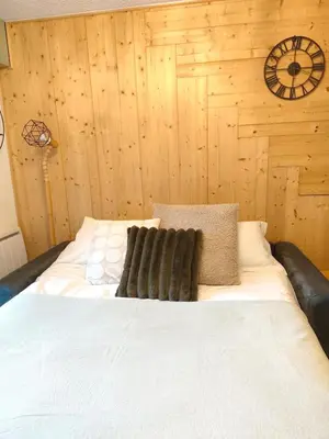 a bed in a room with a wooden wall at Le Nid d'Amélie Studio 4 people mountain view in Combloux