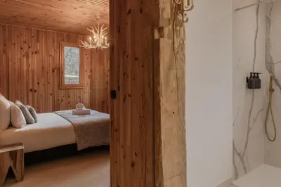 a bedroom with wooden walls and a bed and a chandelier at Chalet Paris Mont-Blanc Luxe et authenticite in Saint-Gervais-les-Bains