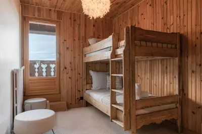 a bedroom with two bunk beds and a chandelier at Chalet Paris Mont-Blanc Luxe et authenticite in Saint-Gervais-les-Bains