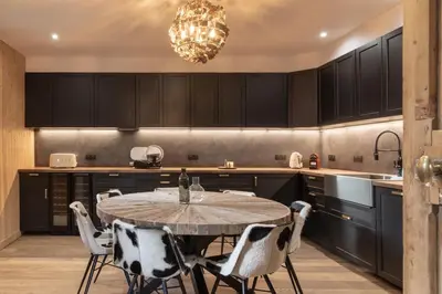 a kitchen with black cabinets and a table and chairs at Chalet Paris Mont-Blanc Luxe et authenticite in Saint-Gervais-les-Bains
