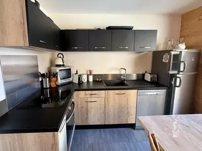 a kitchen with black counters and a stainless steel refrigerator at Appartement lumineux 3 pièces proche des pistes avec WiFi et parking - FR-1-572-343 in Arâches-la-Frasse
