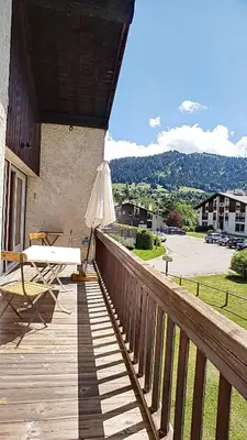 a wooden balcony with an umbrella and a table at Riante Colline Edelweiss - PROCHE CENTRE 3 chambres- balcon in Megève