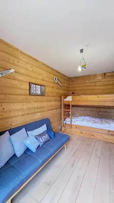 a living room with a blue couch and a bed at Les Perchets - PROCHE CENTRE - 2 chambres in Megève