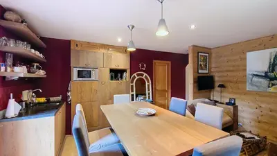 a kitchen and dining room with a wooden table and chairs at Les Perchets - PROCHE CENTRE - 2 chambres in Megève