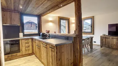 a kitchen with wooden cabinets and a table in a house at Primeveres 1 - JAILLET - PROCHE CENTRE - in Megève
