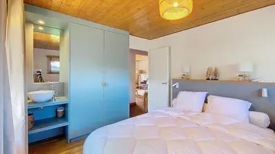 a bedroom with a large white bed and a bathroom at Saint Michel - JAILLET - grand 3 chambres in Megève