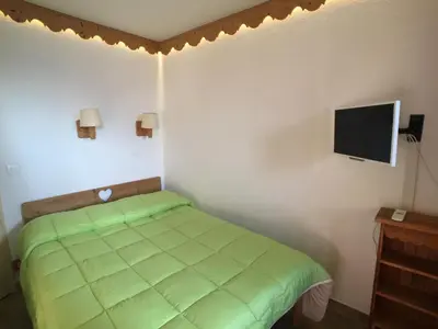 a bedroom with a green bed and a flat screen tv at Chamonix Holiday Cromotherapy Apartment 1 in Chamonix-Mont-Blanc