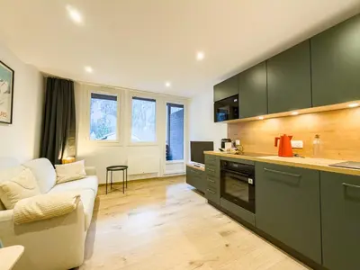 a kitchen with green cabinets and a white couch at Studio exceptionnel, tout équipé face à l'aiguille du midi in Chamonix-Mont-Blanc