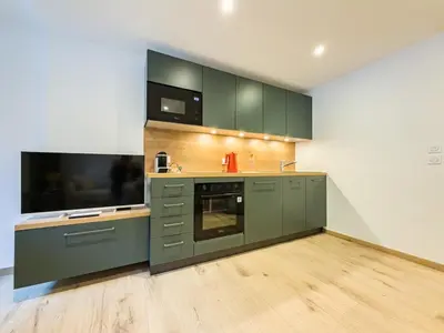 a large kitchen with green cabinets and a television at Studio exceptionnel, tout équipé face à l'aiguille du midi in Chamonix-Mont-Blanc