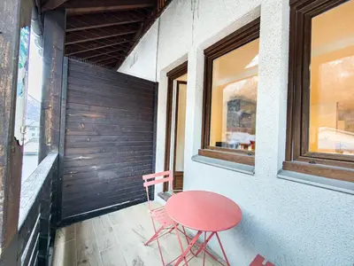 a red table and two chairs sitting on a porch at Studio exceptionnel, tout équipé face à l'aiguille du midi in Chamonix-Mont-Blanc