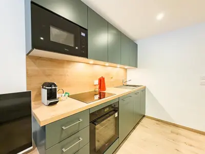 a kitchen with green cabinets and a microwave at Studio exceptionnel, tout équipé face à l'aiguille du midi in Chamonix-Mont-Blanc