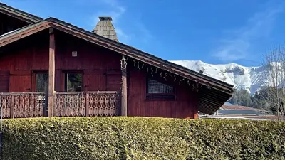 a wooden house with a balcony and a snow covered mountain at Red Fir Chalet in Megève