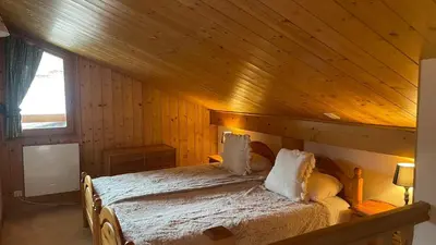 a bedroom with a bed with a wooden ceiling at Red Fir Chalet in Megève
