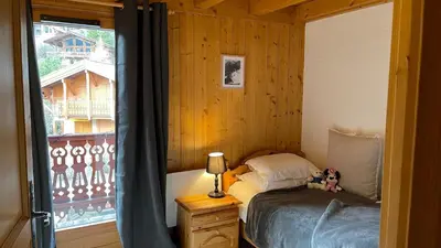 a bedroom with a bed with a teddy bear sitting on it at Red Fir Chalet in Megève