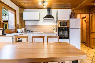 a kitchen with a wooden table and white appliances at Renovated Apartment 7p Argentière - Close to Slopes! in Chamonix-Mont-Blanc