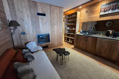 a living room with a couch and a kitchen at Le Menhir Chalets de Lady in Megève
