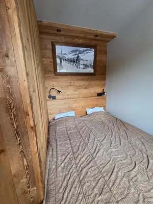 a bedroom with a bed with a wooden wall at Le Menhir Chalets de Lady in Megève