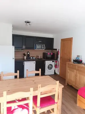 a kitchen with a wooden table and a kitchen with black cabinets at Grand Panorama-au pied du télécabine le Valléen-4pers in Saint-Gervais-les-Bains
