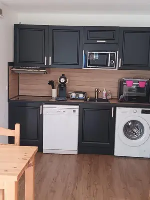 a kitchen with black cabinets and a washer and dryer at Grand Panorama-au pied du télécabine le Valléen-4pers in Saint-Gervais-les-Bains