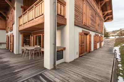 a wooden deck with a table and chairs on a house at Kara Gypaete - Charme - Proche village in Megève