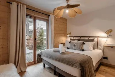 a bedroom with a bed and a large window at Kara Gypaete - Charme - Proche village in Megève