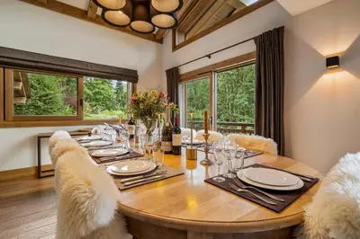 a dining room with a wooden table and chairs and windows at Luxury Chalet Sauna Cinema Mont Blanc Views in Megeve in Megève