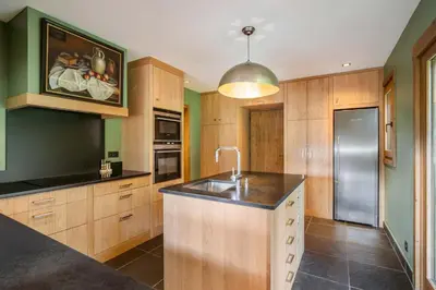 a kitchen with wooden cabinets and a stainless steel refrigerator at Luxury Chalet Sauna Cinema Mont Blanc Views in Megeve in Megève