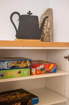 a shelf with board games and a teapot at Appartement lumineux - 8 personnes - Wifi - Lave-linge - Au pied des pistes et des transports in Chamonix-Mont-Blanc