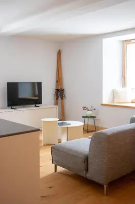 a living room with a couch and a tv at Appartement lumineux - 8 personnes - Wifi - Lave-linge - Au pied des pistes et des transports in Chamonix-Mont-Blanc