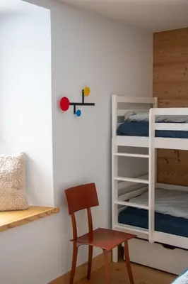a bedroom with two bunk beds and a chair at Appartement lumineux - 8 personnes - Wifi - Lave-linge - Au pied des pistes et des transports in Chamonix-Mont-Blanc