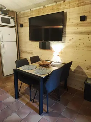 a dining room with a table with chairs and a flat screen tv at Le pied des pistes télésiège des chattrix in Saint-Gervais-les-Bains
