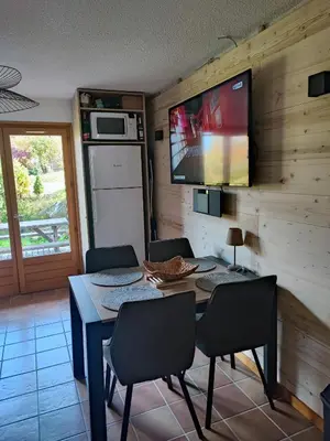 a dining room with a table and a tv on a wall at Le pied des pistes télésiège des chattrix in Saint-Gervais-les-Bains