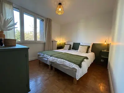 a bedroom with a bed and two windows at Appartement Mélèzes in Megève