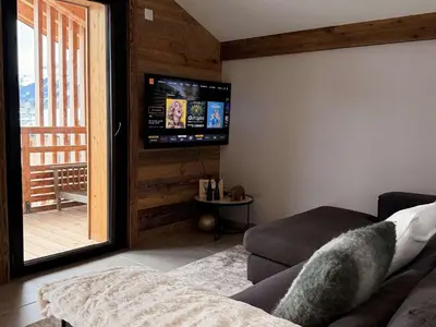 a living room with a couch and a flat screen tv at Appart neuf 3 ch 8 pers près patinoire avec balcon et parking - FR-1-572-347 in Arâches-la-Frasse