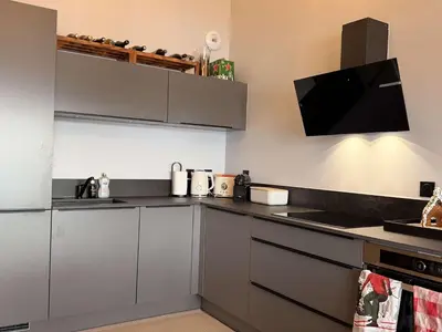 a kitchen with grey cabinets and a flat screen tv at Appart neuf 3 ch 8 pers près patinoire avec balcon et parking - FR-1-572-347 in Arâches-la-Frasse