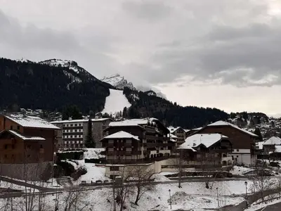 a town with snow covered buildings and a lake at Appart neuf 3 ch 8 pers près patinoire avec balcon et parking - FR-1-572-347 in Arâches-la-Frasse
