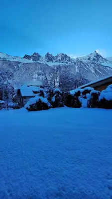 a field covered in snow with a house and mountains at Chalet Inouk 4 people Chamonix center in Chamonix-Mont-Blanc