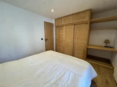 a bedroom with a large white bed and wooden cabinets at Les Carroz - Rénové - Au cœur de la station - 4 pers in Arâches-la-Frasse