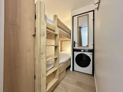 a room with a bunk bed and a door with a washer at Appartement cosy 2 pièces, terrasse, casier à skis, parking commun - FR-1-597-198 in Demi-Quartier