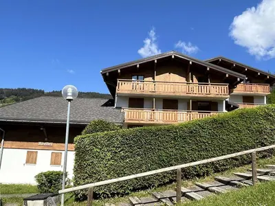 a house with a balcony on the side of it at Appartement cosy 2 pièces, terrasse, casier à skis, parking commun - FR-1-597-198 in Demi-Quartier