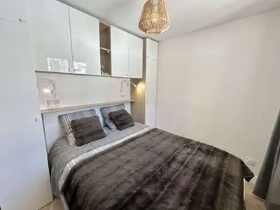 a bedroom with a large bed with white cabinets at Appartement cosy 2 pièces, terrasse, casier à skis, parking commun - FR-1-597-198 in Demi-Quartier