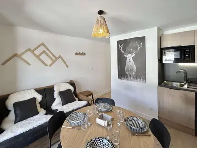 a living room with a table and a couch at Appartement cosy 2 pièces, terrasse, casier à skis, parking commun - FR-1-597-198 in Demi-Quartier