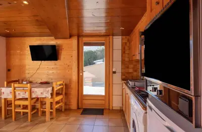 a kitchen with a table and a dining room with a television at Appartement Le Daguet in Sallanches