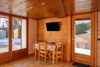 a dining room with a table and a tv on a wall at Appartement Le Daguet in Sallanches