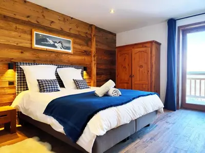 a bedroom with a large bed with a wooden wall at Les trois Massifs in Saint-Gervais-les-Bains