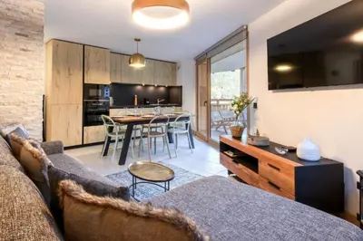 a living room with a couch and a kitchen with a table at Bright apartment ideal in Les Houches for 4 in Les Houches