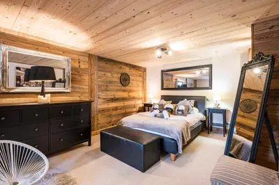 a bedroom with a bed in a room with wooden walls at Chalet Etelley - Jacuzzi Privé in Samoëns