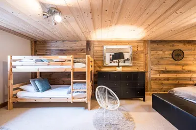 two bunk beds in a room with wooden walls at Chalet Etelley - Jacuzzi Privé in Samoëns
