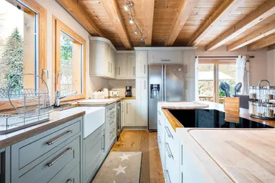 a kitchen with white cabinets and a wooden ceiling at Chalet Etelley - Jacuzzi Privé in Samoëns